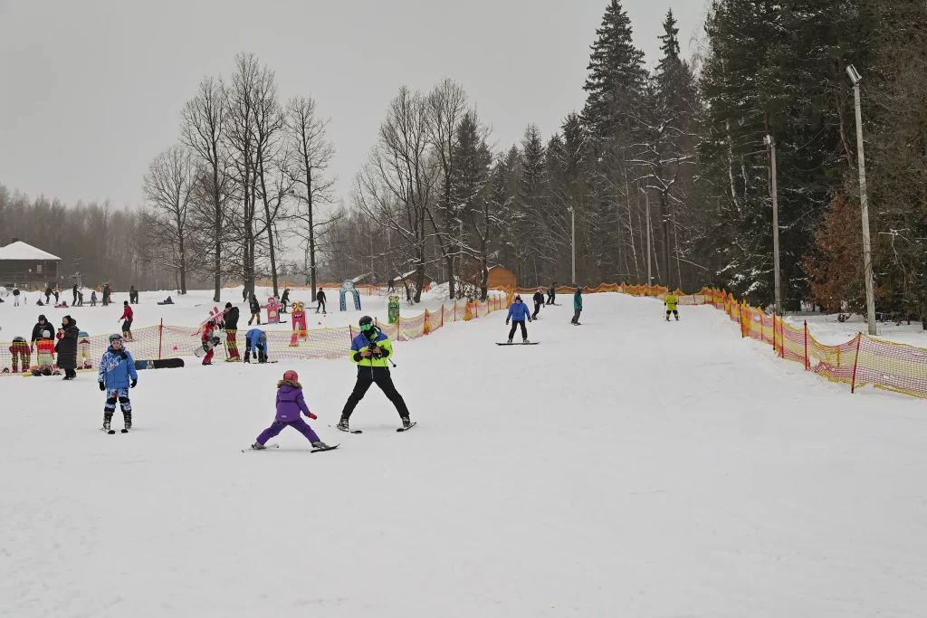 Люди катаются на лыжах и сноуборде в Логойске, Беларусь