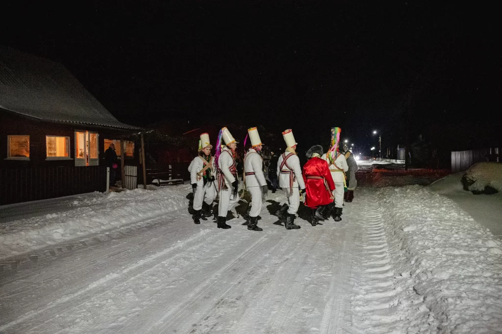 Цари-солдаты маршируют от дома жителя деревни Семежево во время обряда "Калядныя цары", Беларусь